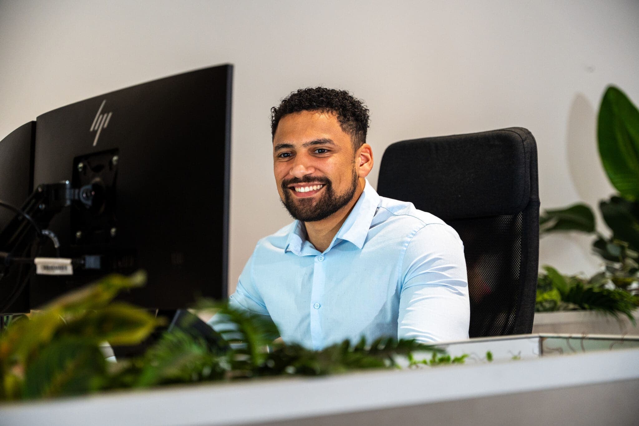 Man lacht achter zijn computerscherm tussen de planten, voor ConnectYou