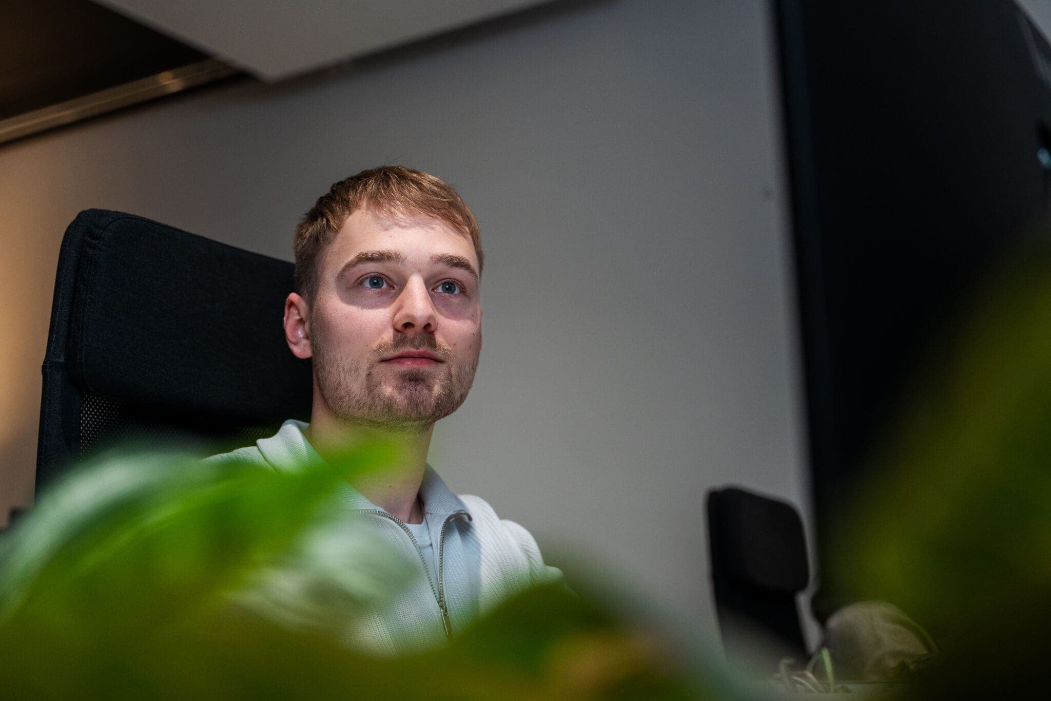 Jonge medewerker zit achter zijn bureau tussen bladeren, ConnectYou