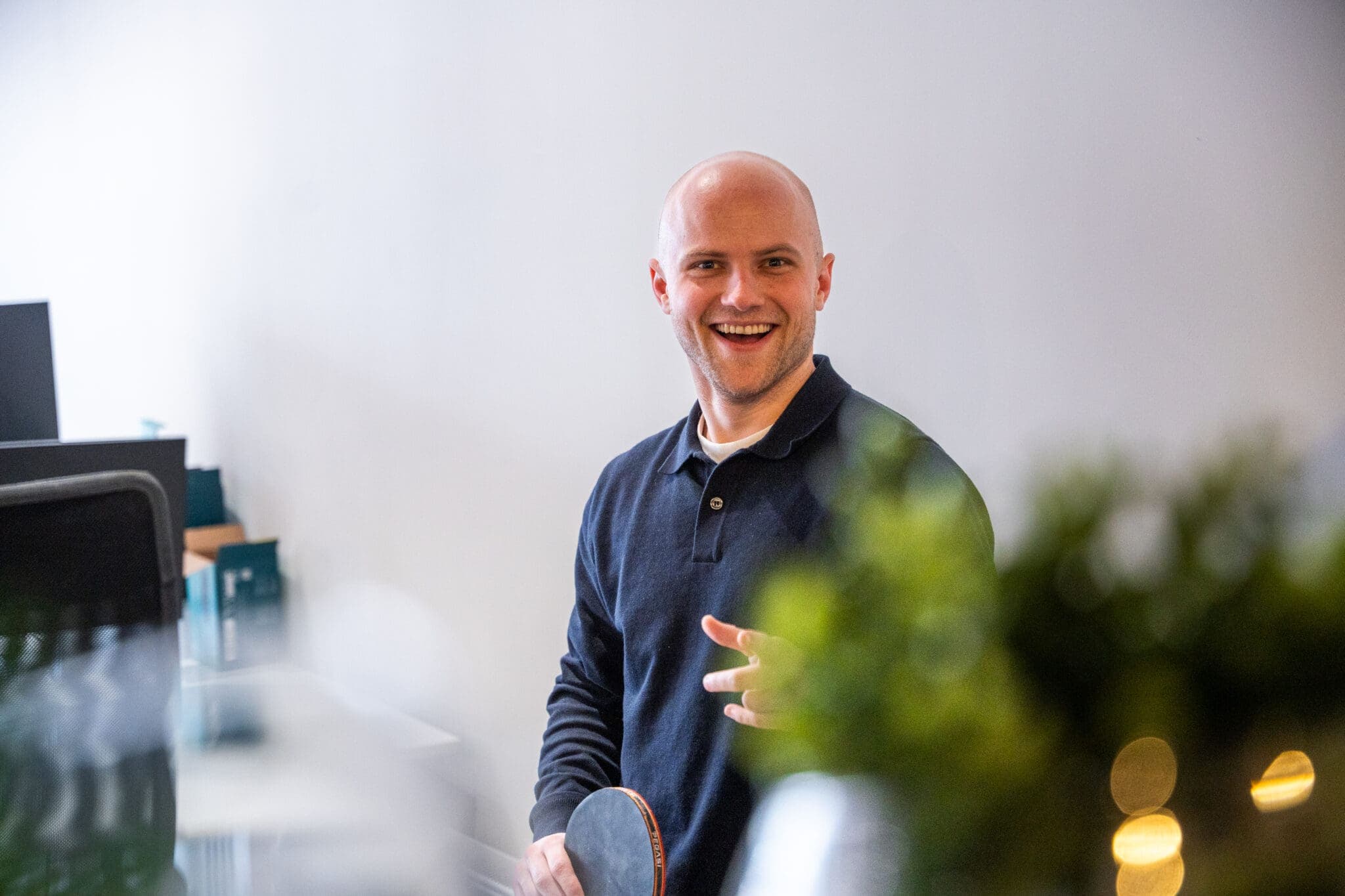 Lachend teamlid van ConnectYou met een tafeltennisbat op kantoor
