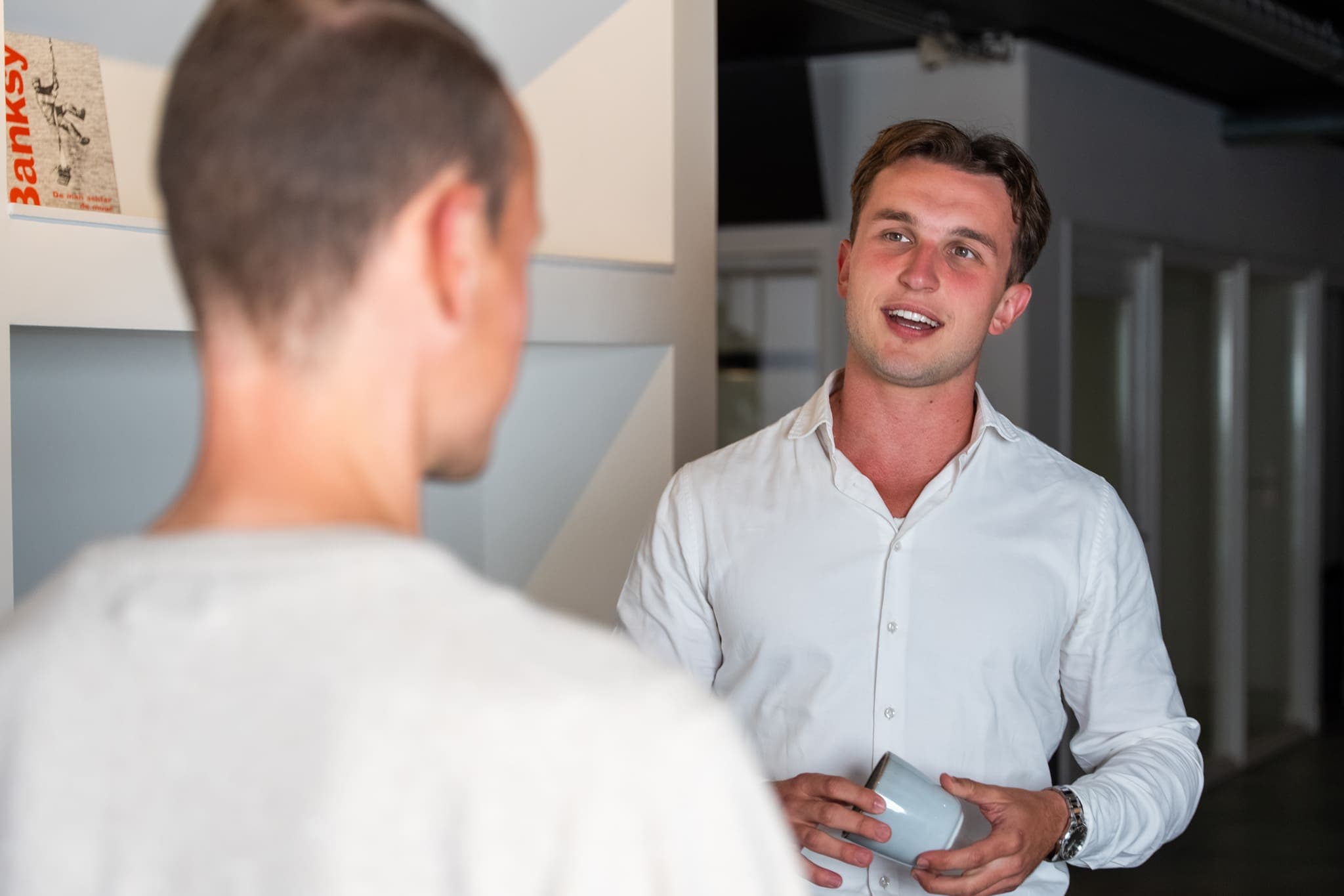 Man in wit overhemd praat met een collega, ConnectYou