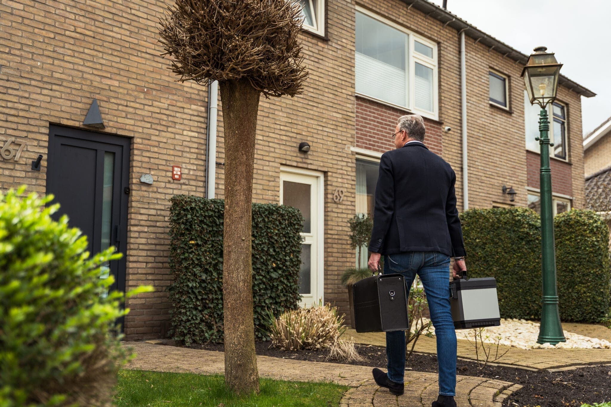 Man loopt met twee koffers naar een woning, voor TrapXpress