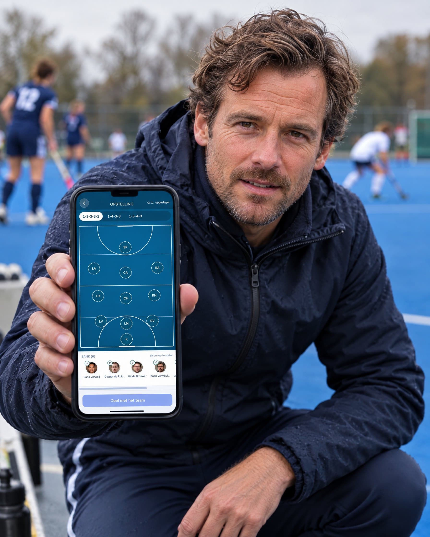 Hockeytrainer toont de Assistje-opstelling op zijn telefoon langs het veld