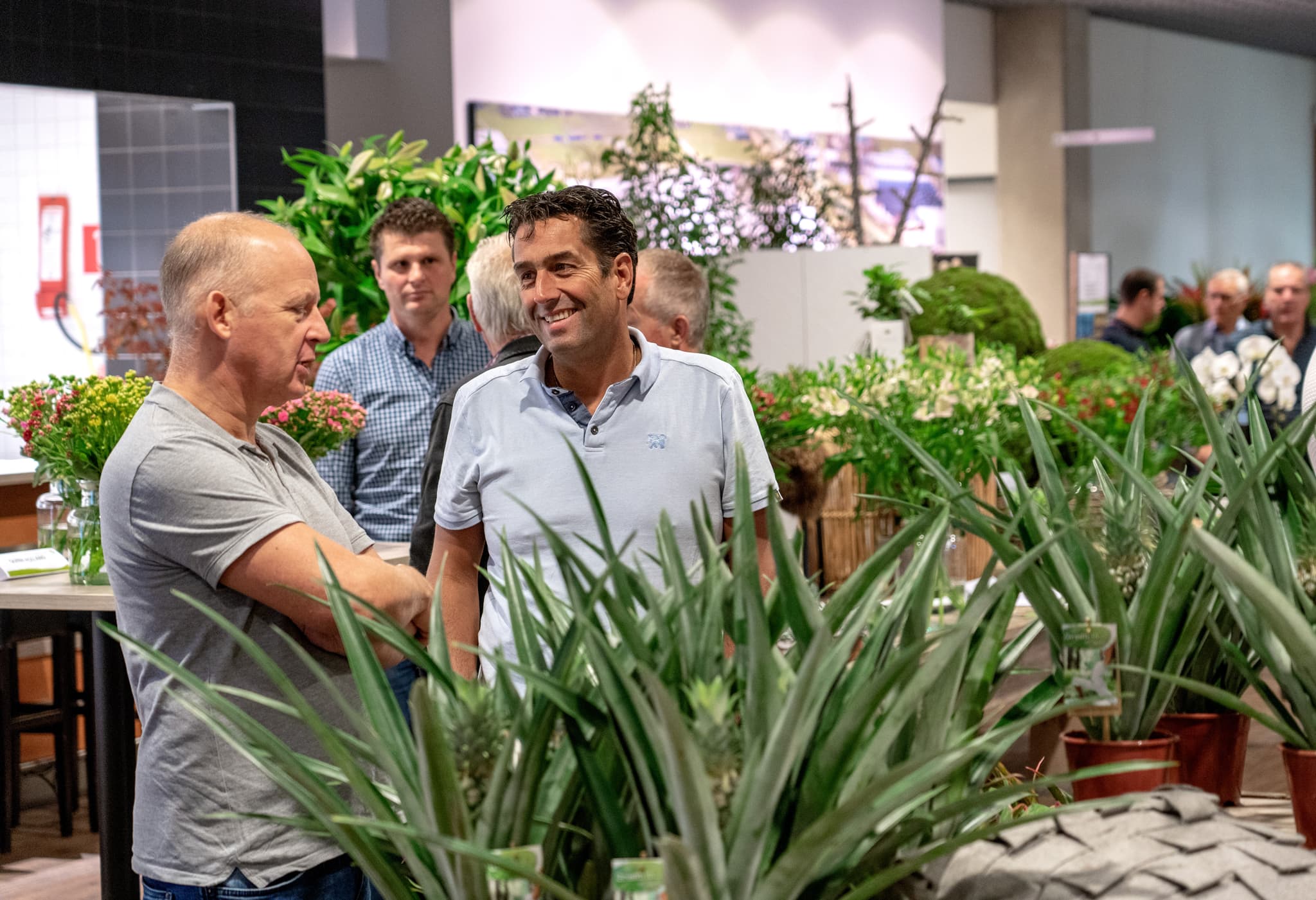 Gesprek tussen mannen op een vakbeurs tussen planten, Plantion